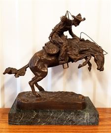 High quality late 20th century solid cast bronze sculpture of a cowboy on a bucking horse, from the original entitled "Bronco Buster" by Frederic Remington, on a green marble base, 10 1/2" x 10" x 6"