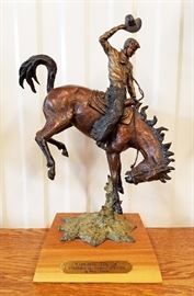 Painted bronze sculpture of a cowboy riding a bucking horse, #30/250,entitled "Cowboy Tough-University of Wyoming Athletics", by Christopher J. Navarro (Wyoming, 1956-), 15" x 11" x 4 1/2". This is a maquette of the monumental sculpture created by the artist for the War Memorial Stadium at the University of Wyoming.
