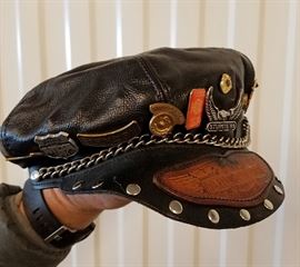 Vintage Harley Davidson cap with tooled leather brim, covered with 1980s/90s pins and badges, many from Sturgis.