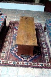 Antique primitive bench with folding bracket legs and Oriental area rug.
