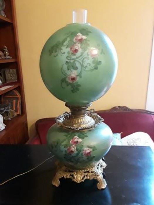 Absolutely gorgeous and unique Gone with the Wind lamp. Top and bottom globes light. This description is what we think is accurate to this lamp. We have not had an expert look at it in person but anyone with antique lamp knowledge can tell this is a beautiful old lamp. Call auction contact if you would like photos emailed, which are better resolution than website.

Appears to be an actual oil lamp that was converted to electricity.  The font appears to be The New Juno by Edward Miller. The font can may be one that was used by The Consolidated Lamp & Glass Co. The decorations and chimney hole suggests Fostoria Glass Co.

Globe shade appears to be a replacement, but has been painted to match wonderfully. 