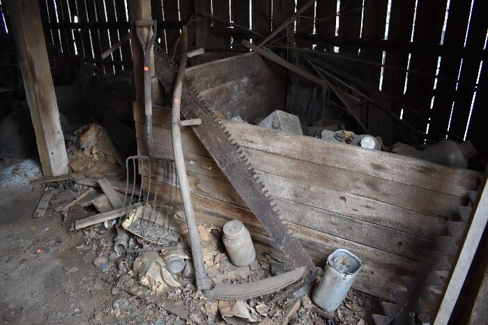 A  few items of Primitive Tools pictured inside the old Barn including an Antique 2 Man Saw, Large Scythe, and Hay Fork. Notice the Crib behind it is loaded with old Jars, Bottles, and More!!!