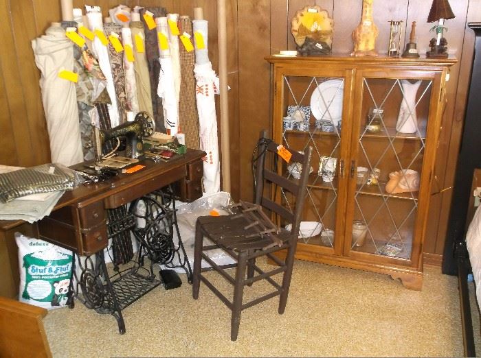 Singer treadle sewing machine and rolls of fabric; two door cabinet w/leaded glass doors