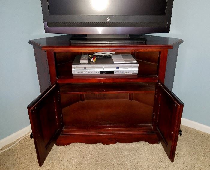 Bassett Furniture:  Corner TV stand, solid wood, dark cherry, shelf and double-door storage area.  42" wide, 19.5" deep, 29.5" tall.