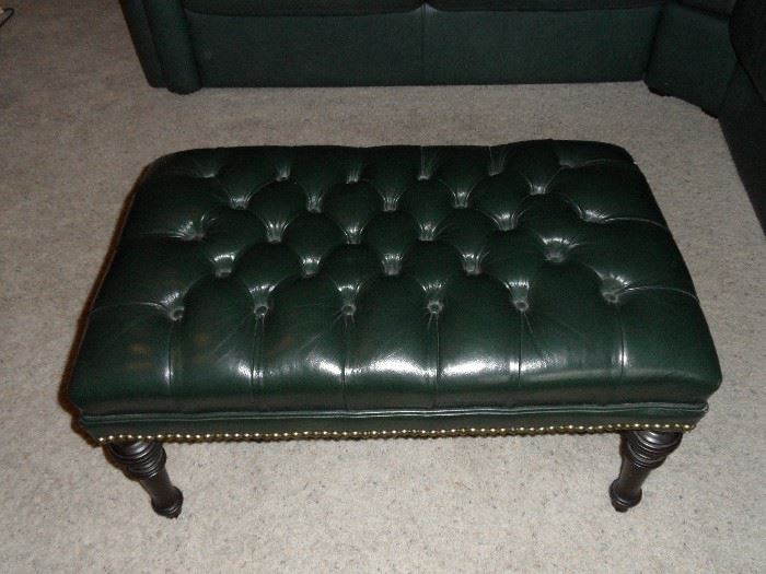 Dark green leather, tufted top, ottoman with nail-head trim and dark wood legs.  30" x 18" x 15" tall.