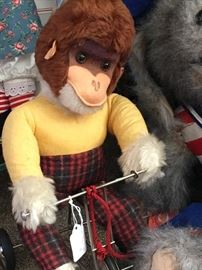 Vintage stuffed monkey riding tricycle pull-toy with glass eyes.