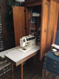 Sewing machine cabinet with drop-down sewing machine and table; room inside for supplies