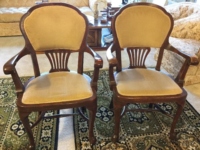 Pair arm chairs with curled carving detail on arms, on rollers