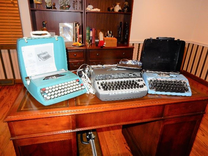 Executive Deak, 3 vintage typewriters, and a pair of book/storage shelving units.