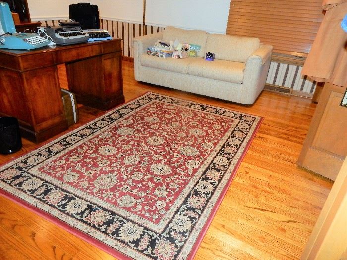 Area rug,  beige sleeper sofa, executive desk, office supplies we have it all in the den.