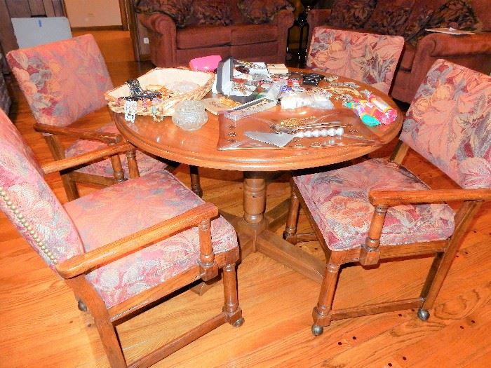 Oak game table with 4 upholstered chairs, chairs are on casters and have nail head trim,