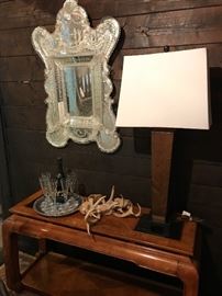 A beautiful Venetian mirror Circa 1920 hangs above a pecan council table with a tall lamp balancing the space 