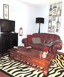 Burgundy Loveseat, Coffee Table, Zebra Themed Rug, Black Chest and Flat Screen TV