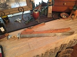  Vintage machete with  leather scabbard by Noriega E. Hijos. Inscribed  in Spanish “Get used to death before death comes, because only living, the living being dies.”
 Bone pommel with forged Eaglehead.