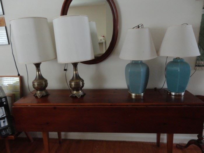 Many lamps, mirrors on a double drop leaf long sofa table