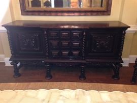 Heavily carved early 1900s Brazilian colonial buffet / sideboard has two large doors and three center drawers to provide ample storage. Barley twist accents. 