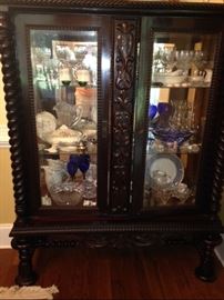 Ornately carved glass china cabinet early 1900s Brazilian colonial piece. Has beveled glass on three sides with glass doors and shelves. Inside back is mirrored. Measures 20 inches deep x 51 inches wide x 63 inches high. 