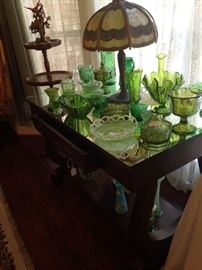Antique table full of green glassware; Tiffany style lamp