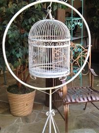 White bird cage on a stand; copper color chair