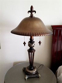 Table lamp with "bronze look" glass shade, dual pull-chain light, metal & composite base and fleur de lis finial.