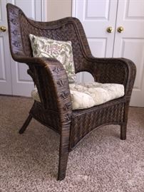Wicker chair with cushion and pillow.