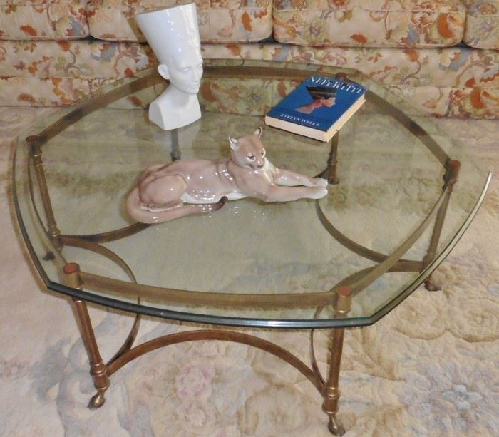 Table sold. Hollywood Regency coffee table. Hexagonal, beveled glass top over brass base with hoof feet. 