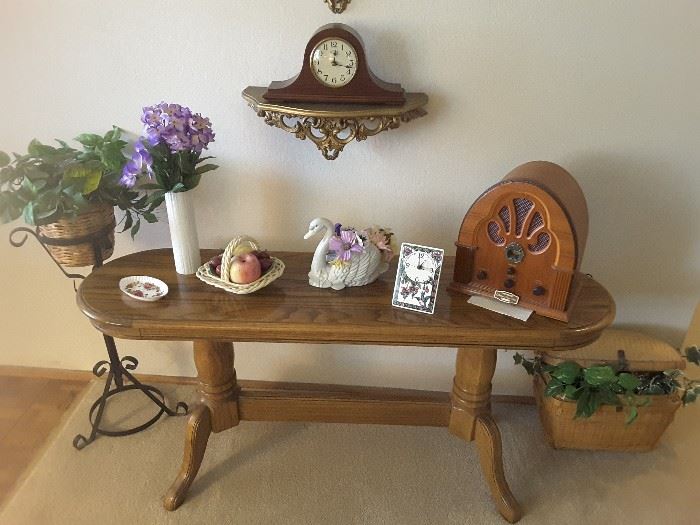 Front Entry Maple Table with Vintage Radio Look a like, Wall Clock, Wrought Iron Plant Stand, Collectible Vases, Fruit Basket, Mini Table Clock, Ring Tray Made in England, and Swan Collectible. Woven Basket for Picnic with Ivy.