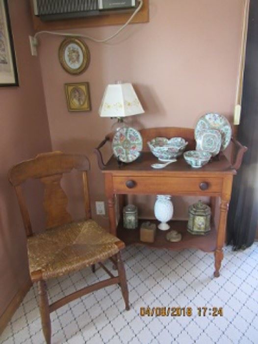 Pine wash stand has oil lamp on top and oriental dishes. The tiger maple rush seat chair.