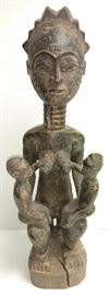 Old or antique African large carved wood maternity maternite statue of a nursing mother with rowed hair, scarification and neck rings seated on a stool and supporting three infants, two on her knees holding her breasts and a third clinging to her back.

We have limited knowledge of this field however our online research indicates this may be a West African Agba sculpture although we have seen somewhat at least to our interpretation related images captioned Yoruba, Baule, Luba, Congo, Nigerian et al.

Carved wood with dark patina.

23 1/4" high x 7" wide x 6 1/8" deep overall.