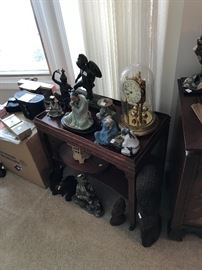 Mantle clock, Asian decor and a small wood table on wheels.
Also, to the left are some vintage binoculars, weather station, and two radios!