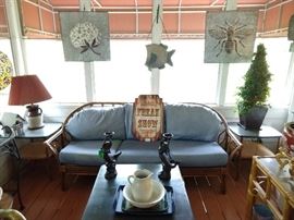 Vintage bamboo sofa, flanked by a pair of desirable Haywood Wakefield bamboo end tables and matching coffee table, pair of cast iron mermaid candleholders, embossed galvanized tin cotton boll and honeybee panels.