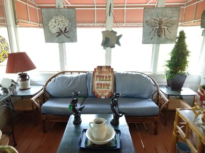 Vintage bamboo sofa, flanked by a pair of desirable Haywood Wakefield bamboo end tables and matching coffee table, pair of cast iron mermaid candleholders, embossed galvanized tin cotton boll and honeybee panels. 