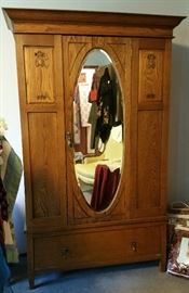 Armoire with floral carving on panels and oval mirror