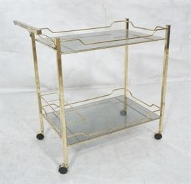 Lot 656 Gold tone Metal Rolling Bar Cart. Glass shelves o