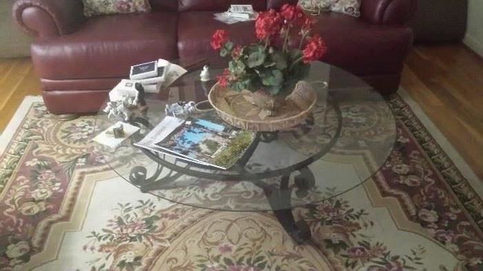 Large round glass and wrought iron coffee table  Living room area rug.