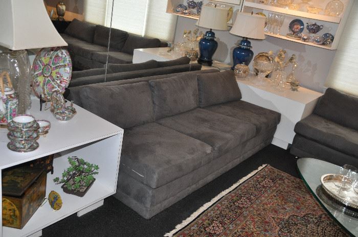 Arm-less 3 seat grey suede sofa nestled in between 2 white Formica end tables, Sofas are 81"w x 24"h x 33"d