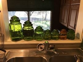 Green glass kitchen canisters with lids in graduated sizes.