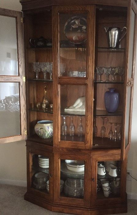 Baker display cabinet filled with luxurious things: Lenox china, Waterford stemware, Vincent Glinsky marble nude, Limoges vase, Kosta Boda vase, and more.
