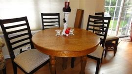 Large antique oak table w/ 3 leaves and 5 legs. 4 black chairs with small leopard print