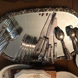Silverplate flatware on a mirrored plateau.