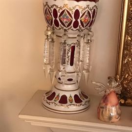Closeup  of one of a pair of antique drop crystal porcelain and ruby glass mantle candlelsticks.