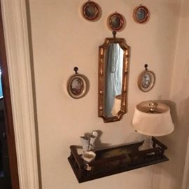 Hanging shelf with mirror and framed vintage art.
