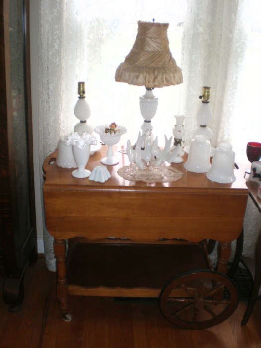 Maple tea cat with drop leaves and lotsof milk glass, inclding a pair of dresser lamps and a lamp with silk shade.