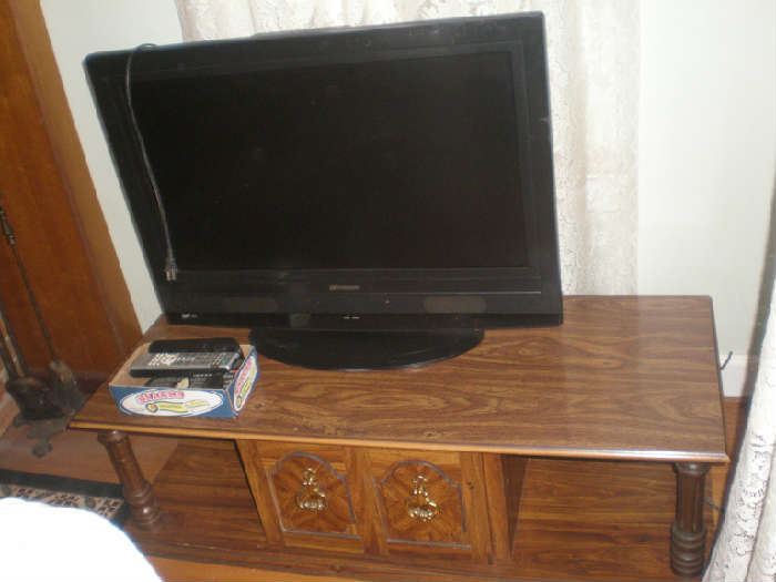 Flat screen tv, box full of remotes. Coffee table.