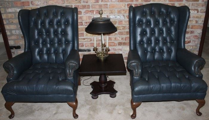 Vintage Green Tufted Leather Queen Anne Wingback Chairs shown with a Vintage Federal Style 3-Light Candlestick Lamp with Metal Shade on top of a small Square Black Pedestal Table