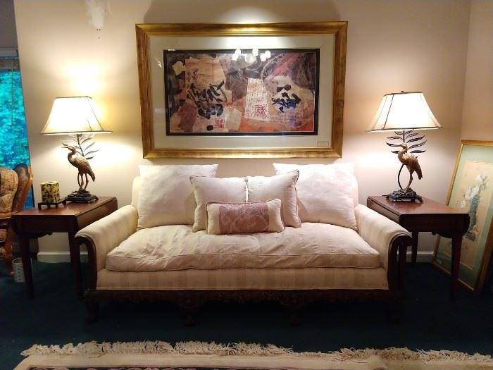 Beautifully carved wooden couch, with down cushion, pair of single drawer drop-leaf mahogany side tables, Pair of crane lamps and well-framed contemporary art.