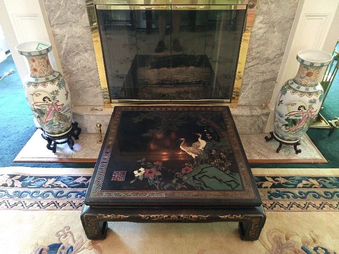 Nice hand carved/painted Asian black lacquer table, with cranes, flanked by a large pair of Asian porcelain vases on wooden stands.