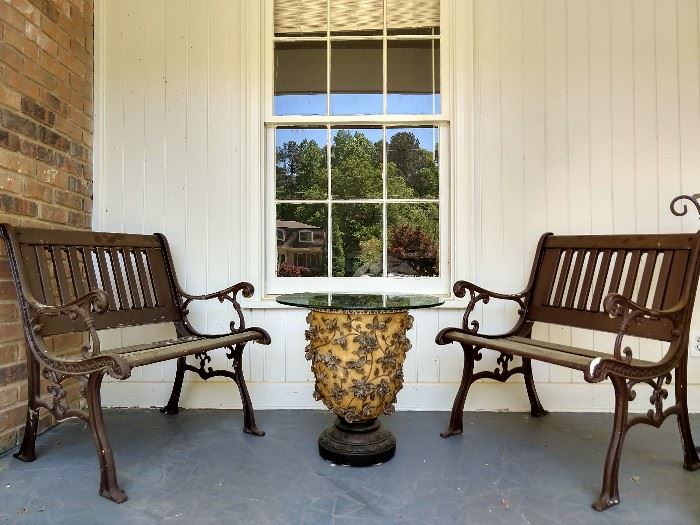 Pair of cast iron love seats, resin urn with glass top.