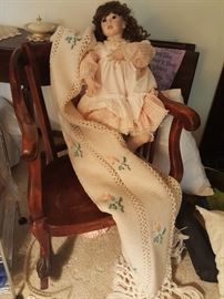 Antique child's rocking chair with doll and blanket.