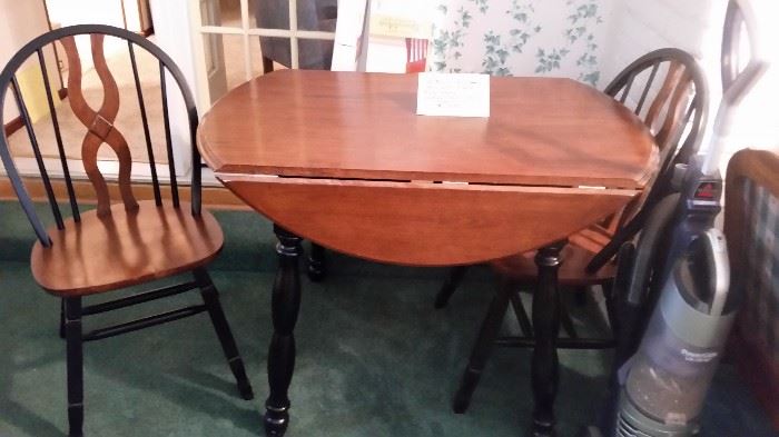 This small lovely drop leaf dinette table  with 2 chairs, are wood with black accents.